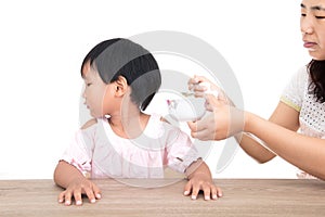 Chinese little girl refuses mother`s feeding in front of white background