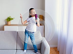 Chinese Little Girl Singing Holding Hairbrush Like Microphone At Home