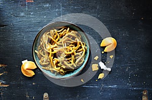 Chinese Lo mein noodles in bowl with fortune cookies top view