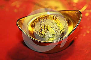 Chinese lucky gold ingot on red calligraphy backgr