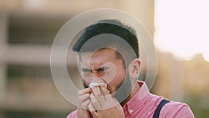 Chinese man in casual clothes snotting with a tissue in the street