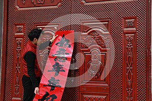 Chinese man post new year`s scrolls , Spring festival couplets and Mars at red door in China