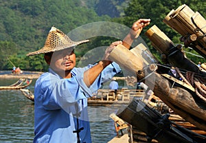 Chinese man preparing bamboo rafts to travel on the River of Nine Bends