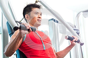 Chinese Man training strength in fitness gym