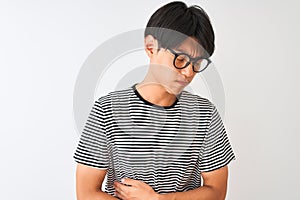 Chinese man wearing glasses and navy striped t-shirt standing over isolated white background with hand on stomach because nausea,