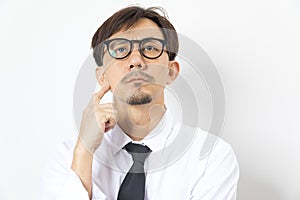 Chinese man wearing white shirt over white background with hand on chin thinking about question.