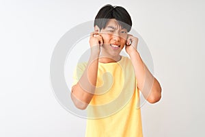 Chinese man wearing yellow casual t-shirt standing over isolated white background covering ears with fingers with annoyed