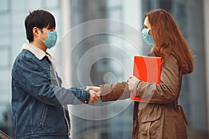 Chinese man and a woman in disposable masks are shaking hands photo