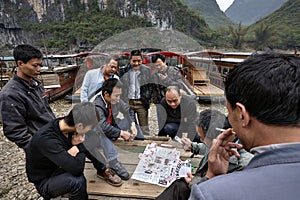 Chinese men, boatmen playing card game near pier, Guangxi, China