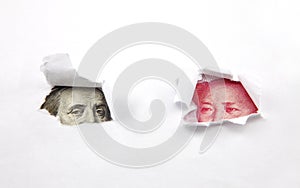 Chinese money and dollar behind two holes in paper photo