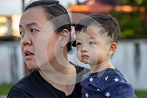 Chinese mother carry her Happy and cute Asian Chinese baby boy at park during evening