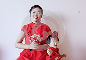 Chinese mother and child in red cheongsam do good luck pose