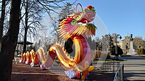 Chinese New Year. Bright red-orange dragon in the park. Traditional Chinese holiday decoration. The dragon`s mouth is open. Long