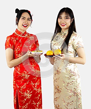 Chinese new year concept. Two Asian women in Cheongsam dres holding plate of tea and oranges