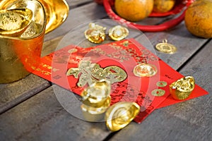 Chinese New Year ornaments with oranges, gold ingots and red envelopes or hong pao on wood background. Selective focus. Chinese