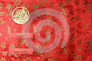 Chinese New Year of the Tiger 2022. Golden tiger symbol on red fabric with traditional chinese ornament birds and dragons.