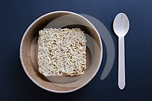 Chinese noodles in an organic paper bowl. Disposable wooden cutlery for eating instant meals