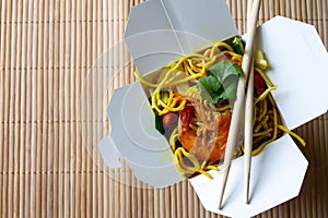 Chinese noodles with shrimps and vegetables in box on bamboo mat. Chinese food concept