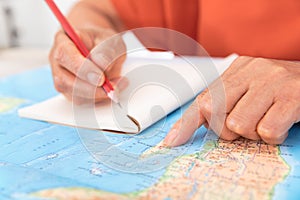 Chinese old man holding a pencil and looking at the world map making travel plans