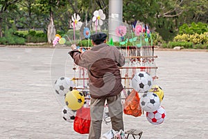 Chinese old man street vendor seller ball and other toys in the Public garden, Nansa, Yunnan, China. Football concept