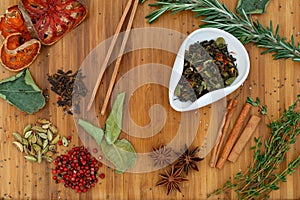 Chinese Oolong dry mix tea in a white bowl. On a wooden board scattered a lot of ingredients for tea.