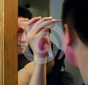 A chinese opera actor is painting his face