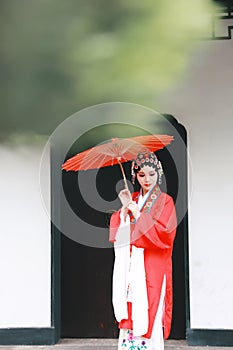 Chinese opera woman.Practicing Peking Opera in the garden With a red umbrella, Colorful, china