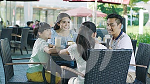 Asian family smiling, eating & drinking outdoor at streetside table