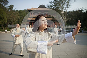Chinese People Practicing Tai Ji in Front of Traditional Chinese Building