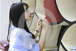 Chinese Portrait of young beautiful woman looking for Book In Bookstore