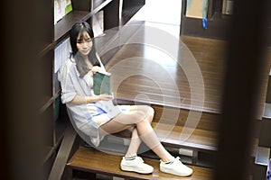 Chinese Portrait of young beautiful woman reads Book In Bookstore