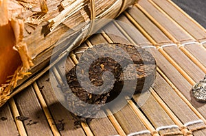 Chinese pressed PU-erh tea in bamboo leaf packaging on a bamboo Mat, close-up, macro