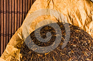 Chinese pressed PU-erh tea on wrapping paper on a bamboo Mat, close-up, macro