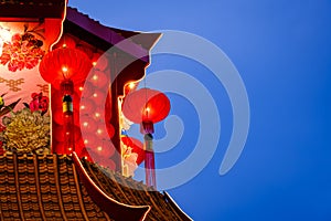 Chinese red lanterns lunar new year decorations hanging on the temple roof with dark blue sky at the background.