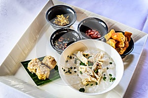 Chinese rice porridge with shredded chicken and spring onions with dough fritters you tiao and dim sum siew mai