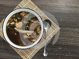 The Chinese roll noodle soup or paste of rice flour in a white cup placed on a bamboo mat dark brown table