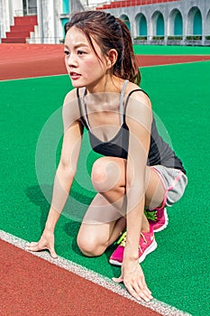 Chinese runner at starting position on racetrack