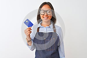Chinese shopkeeper woman wearing glasses holding credit card over isolated white background with a happy face standing and smiling
