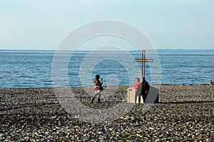 Chinese Singapore tourists at Christian cross crucifix on rocky Black Sea beach seafront Batumi Georgia