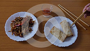 Chinese spring rolls with red sweet and sour sauce, Chinese chopsticks. Asian Chinese cuisine. background with brown