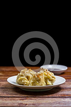 Chinese Steamed Dumpling, Shumai on white dish served with soy sauce on wooden table on black background. Delicious Dimsum pork