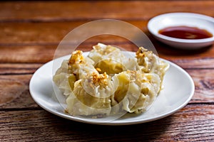 Chinese Steamed Dumpling, Shumai on white dish served with soy sauce on wooden table. Delicious Dimsum pork