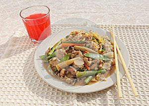 Chinese stir fry dish with red drink and chopsticks