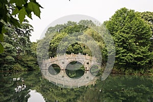 Chinese stone bridge with symetrical reflection in lake
