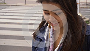 Chinese student typing by laptop outside with road background.