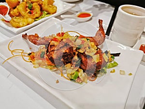 Chinese-style deep fried pigeon with vegatable topping on white dish