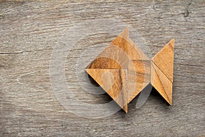 Chinese tangram puzzle in fish shape on wood background