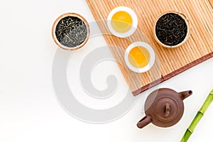 Chinese tea ceremony concept. Tea pot, tea cup, dry tea leaves, bamboo mat on white background top view copy space
