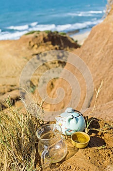 Chinese tea ceremony with porcelain teapot, clay cup. View of nature beach landscape with blue sea on a sunny day