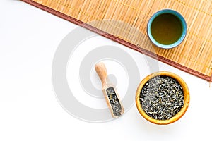 Chinese tea concept. Tea ceremony. Dry tea leaves in bowl and wooden scoop near cup of tea on white background and